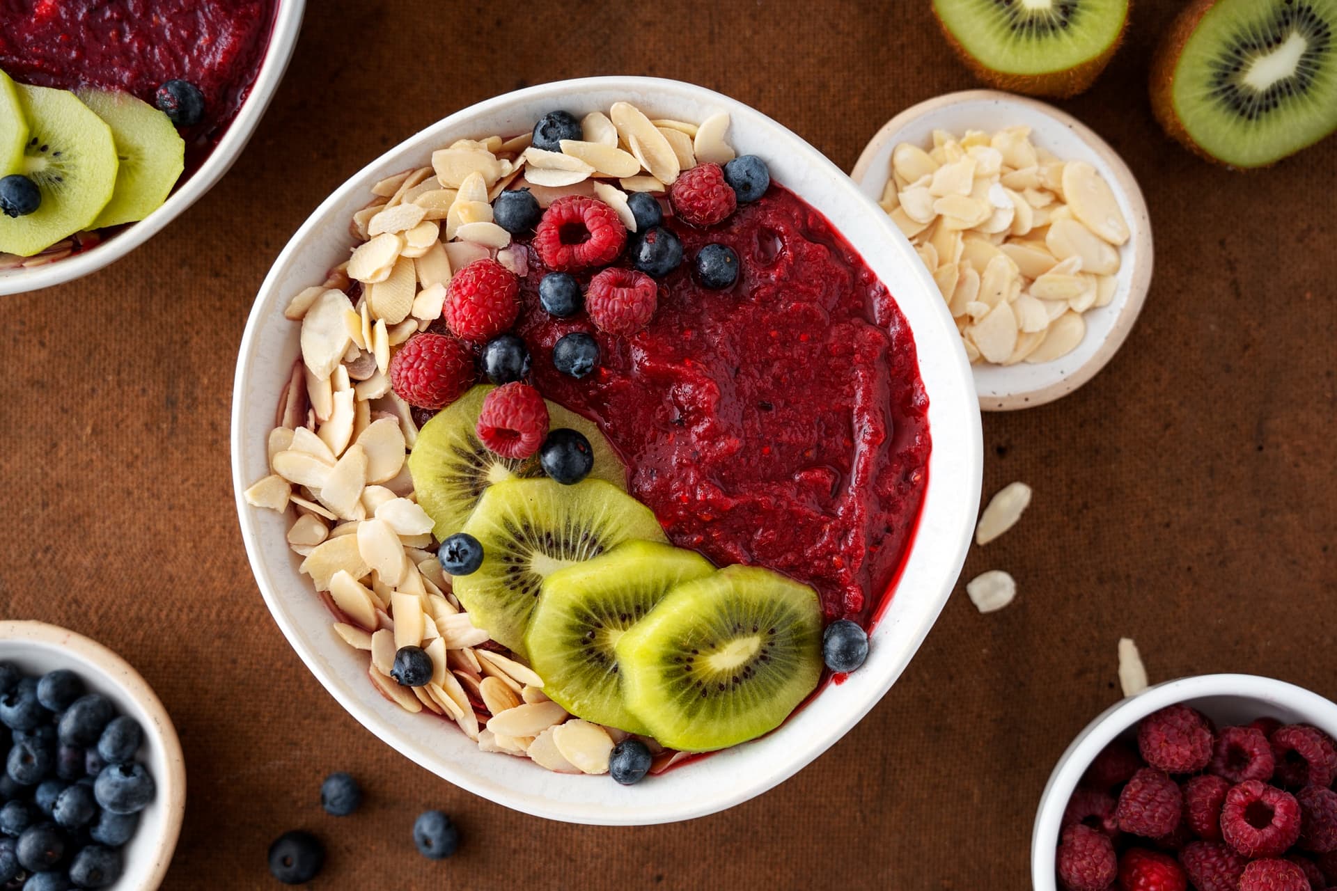Tigela de açaí com frutas frescas e granola em porção individual sobre mesa de madeira